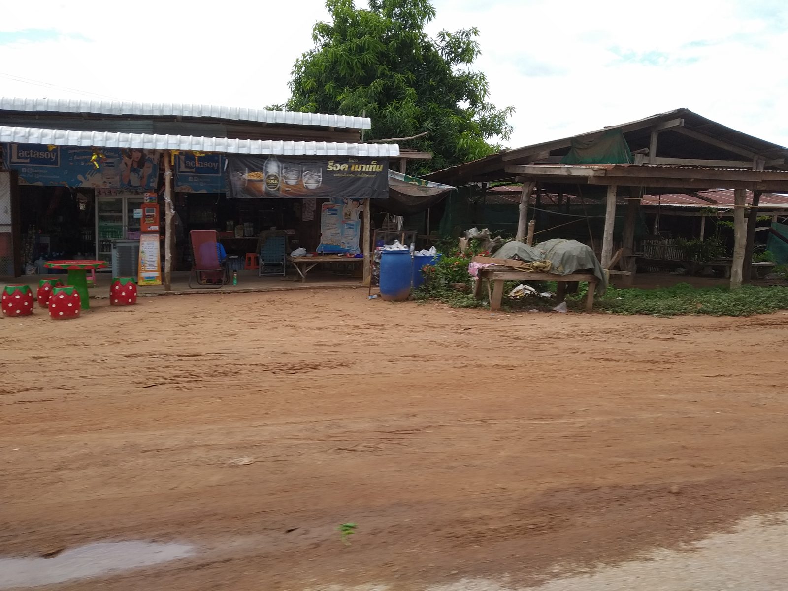 Small roadside shop and shelter on a red dirt road in rural Thailand